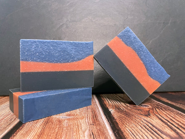 Three layered beer soap bars on a wooden surface with a dark background