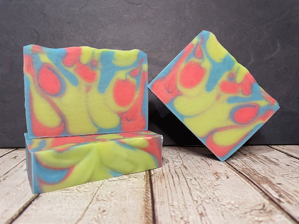 Blue coral and lime colorful tie-dye beer soap bars on a wooden surface with a dark background
