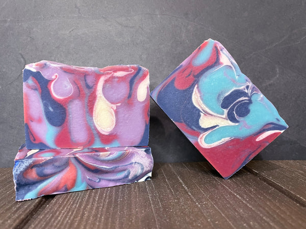 Three colorful beer soap bars with a marbled pattern on a wooden surface.
