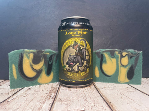 Clover Chaser Lone Pint Brewery beer can with green gold and black beer soap bars on a wooden surface