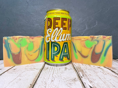 Can of Deep Ellum IPA with colorful swirled beer soap bars on a wooden surface