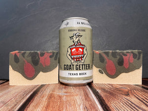 GOAT GETTER TEXAS BOCK 11 below brewing company beer can between two bars of white black grey and red beer soap on a wooden surface with a dark background