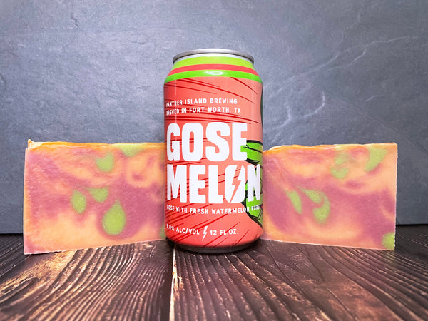 panther island brewing Gose Melon beer can between two marbled green melon and raspberry beer soaps on a wooden surface and dark background