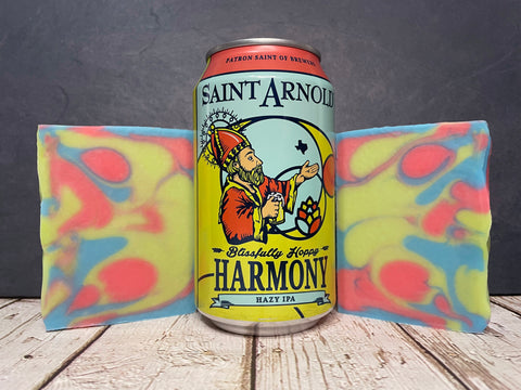 Saint Arnold Harmony Hazy IPA beer can between two colorful beer soaps on a wooden surface