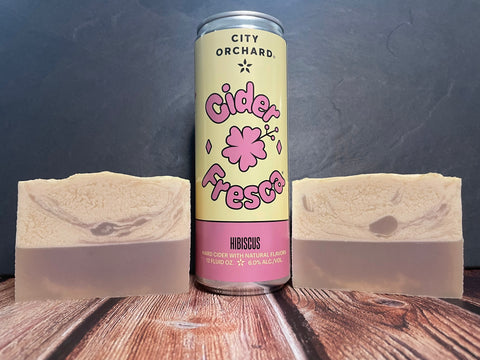 City Orchard hibiscus cider fresca can with two bars of cider soap on a wooden surface