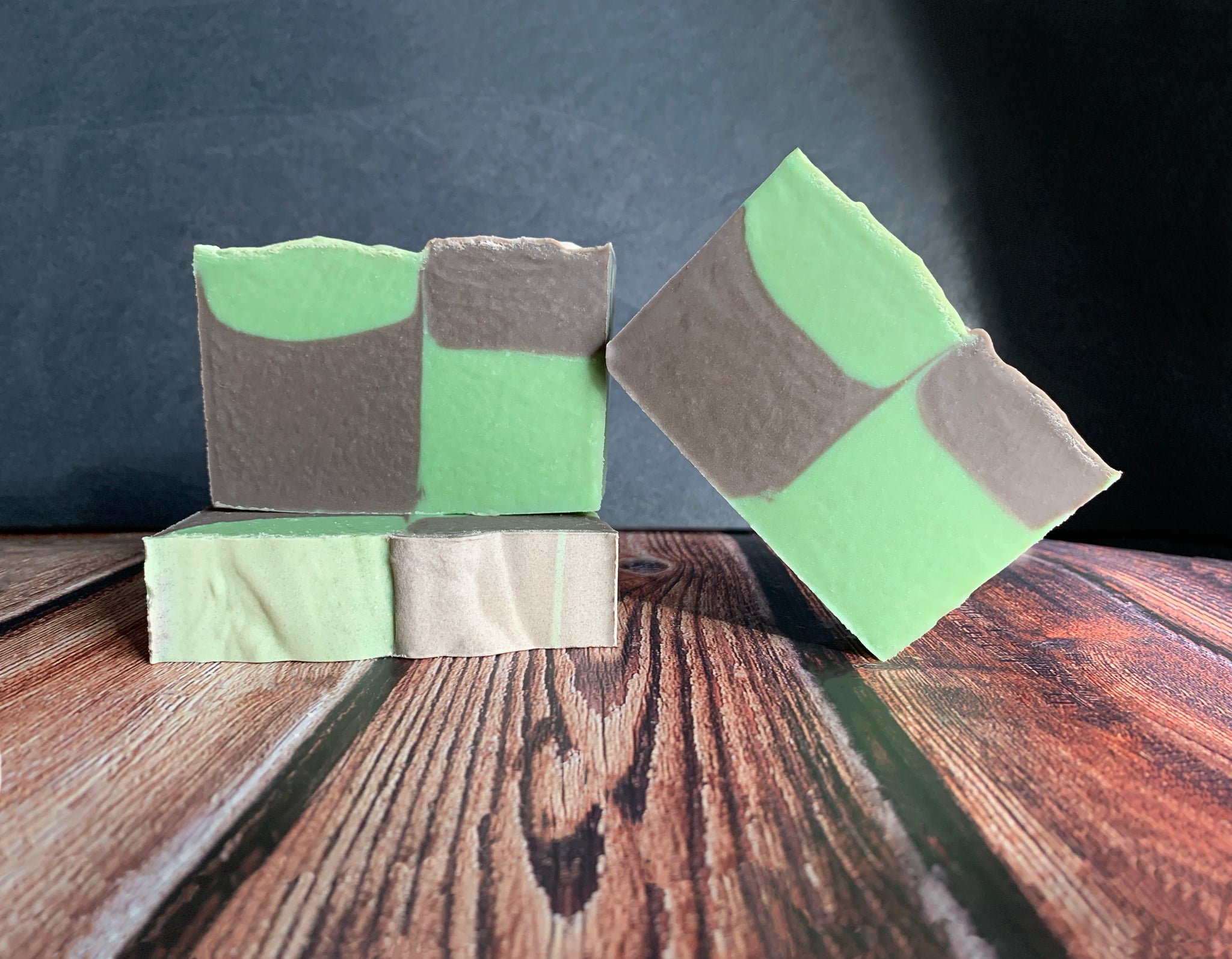 Three bars of beer soap with green and brown checkered color pattern on a wooden surface