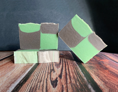 Three bars of beer soap with green and brown checkered color pattern on a wooden surface