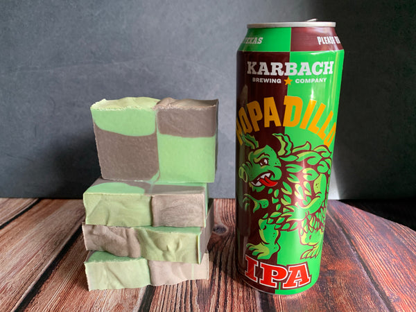 Karbach Brewing Company Hopadillo IPA can with a stack of green and brown beer soap on a wooden surface.