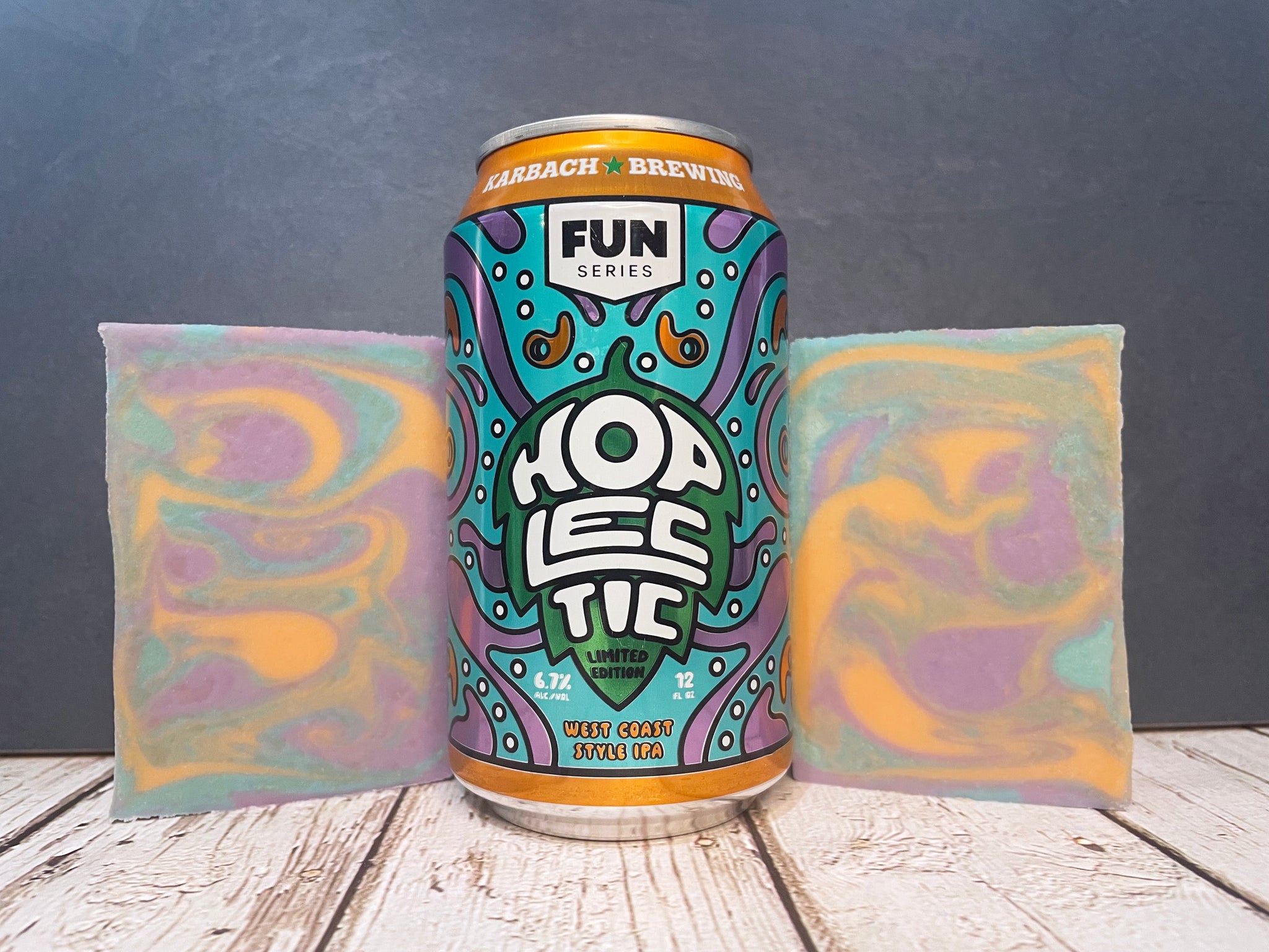 Hoplectic by Karbach Brewing Company beer can between two bars of marbled purple orange and teal beer soap on a wooden surface with a dark background