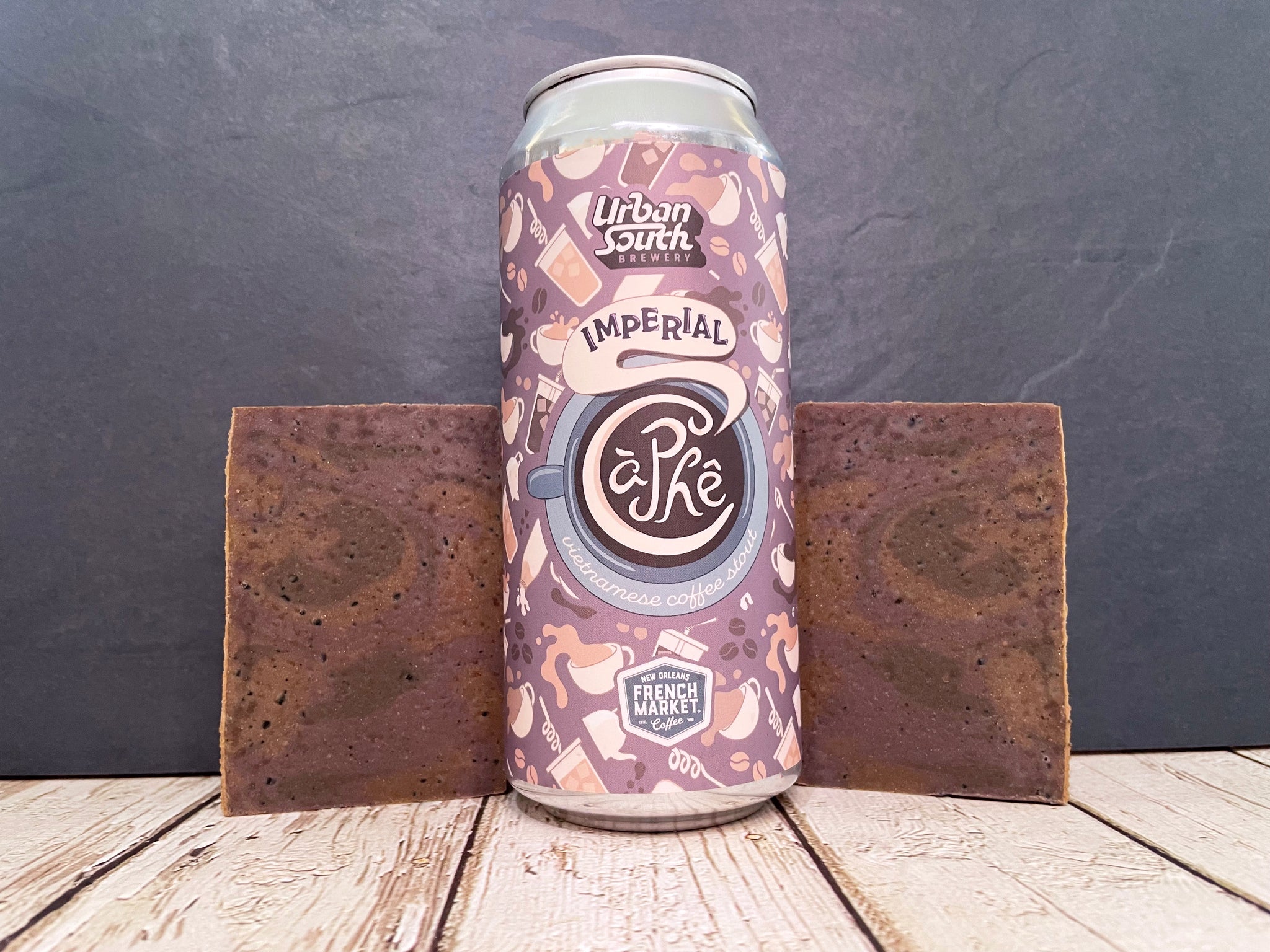 Can of Urban south brewery imperial ca phe between two bars of beer soap made with artisan coffee ground on a wooden surface with a dark stone background