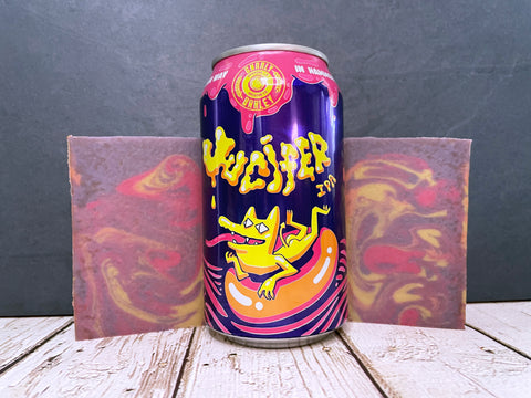 gnarly barley Jucifer IPA beer can between two bars of pink purple and yellow marbled beer soap on a wooden surface with stone background