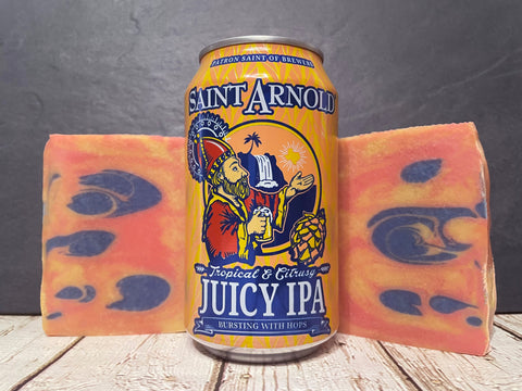 Saint Arnold Juicy IPA can between two orange gold and navy swirl beer soap bars on a wooden surface