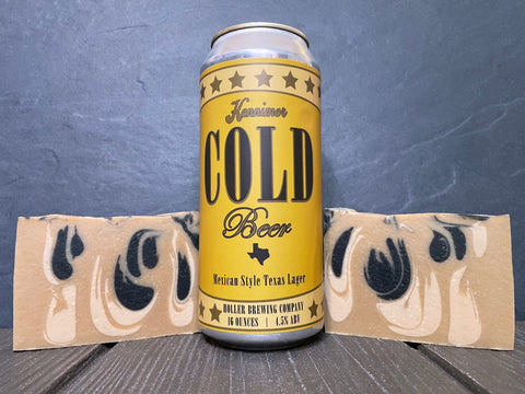 Can of kennimer cold beer by holler brewing company between two bars of gold and black beer soap on wooden surface