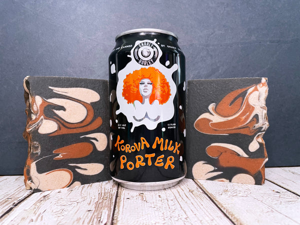 gnarly barley korova milk porter beer can between two bars chestnut cream and black beer soap made with activated charcoal on a wooden surface with dark stone background