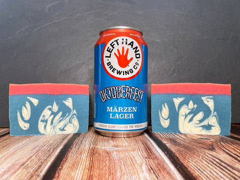 Left Hand Brewing Co. Oktoberfest Märzen Lager can between two red white and blue beer soap bars on a wooden surface.