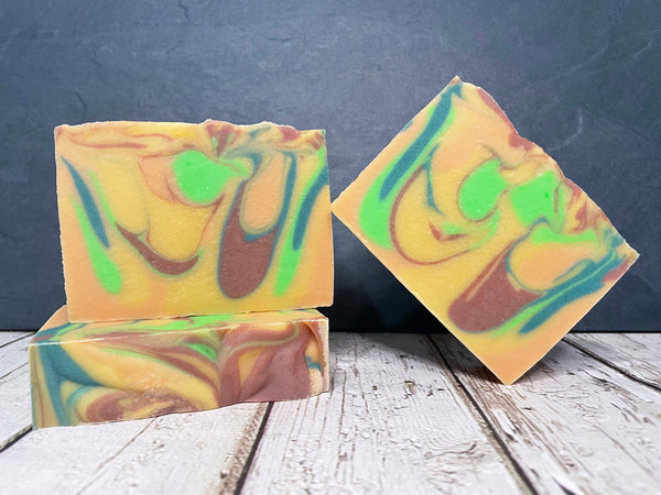 Three colorful beer soap bars with a swirled pattern on a wooden surface 