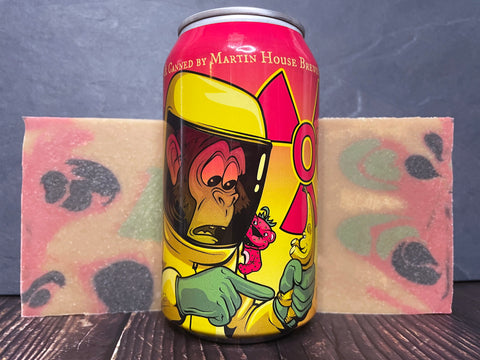 outbreak sour by Martin house brewing company beer Can with cartoon monkey character design on a colorful background between two bars of tie dye beer soap on a wooden surface