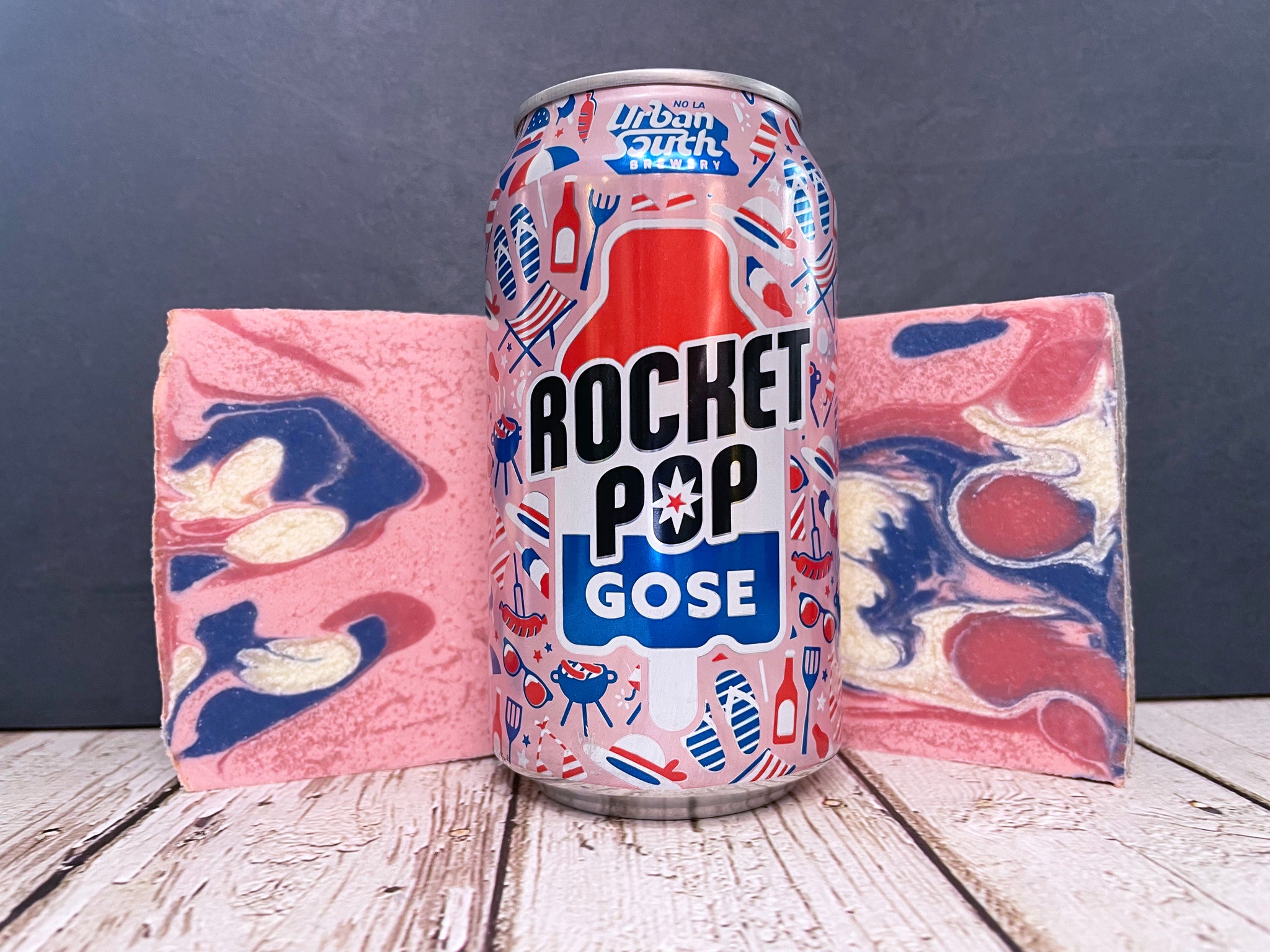 urban south brewery rocket pop beer can between two bars of beer soap on a wooden surface with a stone background