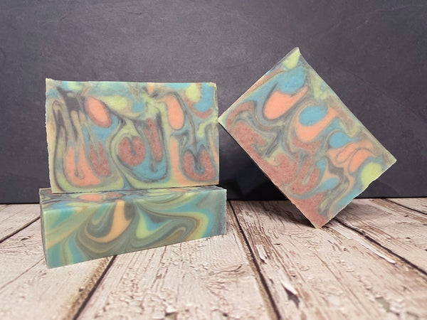 Two colorful beer soap bars with a marbled pattern on a wooden surface.
