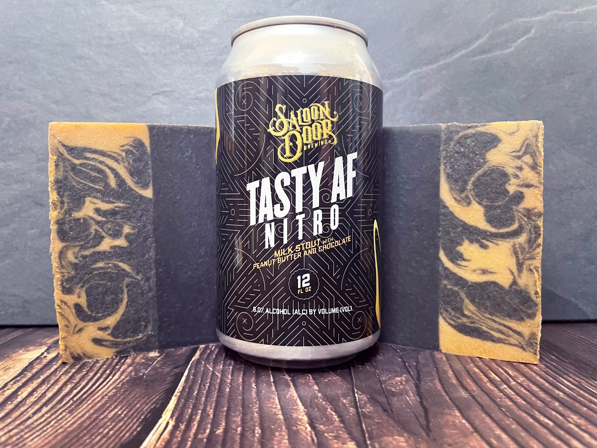 saloon door brewing tasty af nitro beer can between two gold and black bars of beer soap with activated charcoal on a wooden surface