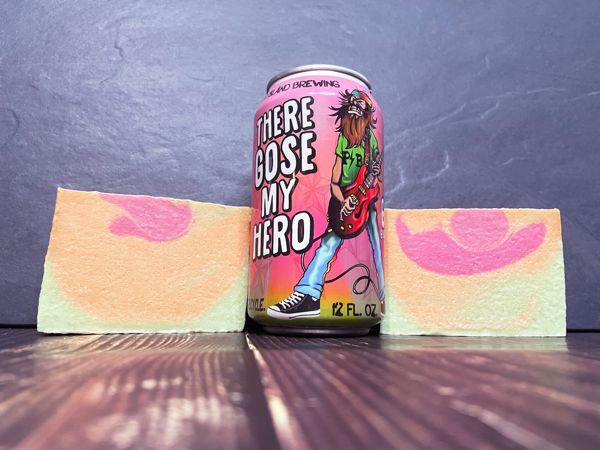 Panther Island Brewing There Gose My Hero Beer can with artistic design between two bars of swirled pink orange and green beer soap on a wooden surface and stone background