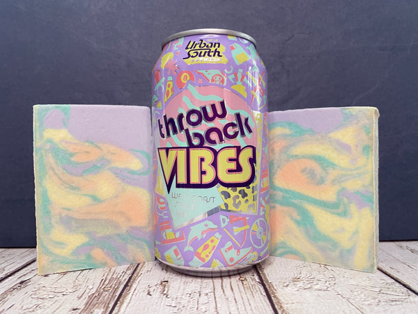 Colorful can of Urban South throwback vibes beer between two marbled bars of beer soap on a wooden surface