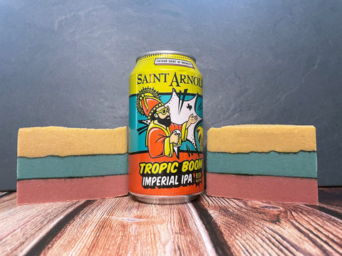 Can of Saint Arnold Tropic Boom Imperial IPA with two bars of beer soap on a wooden surface with a gray background