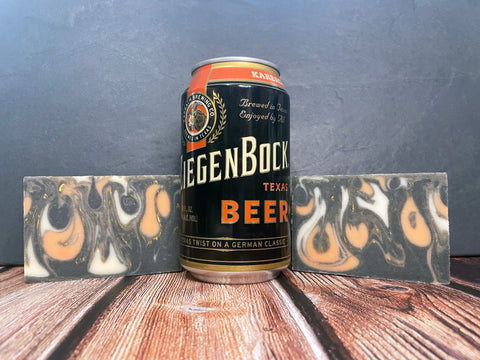 Can of Ziegenbock Texas beer by Karbach Brewing Company with two bars of orange white and black bars of beer soap with activated charcoal on a wooden surface